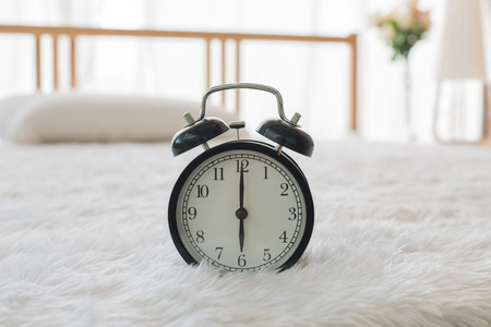 The black alarm clock rings  in the morning in the home.