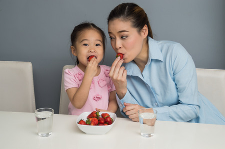 Parents and children are eating strawberries happily.の写真素材