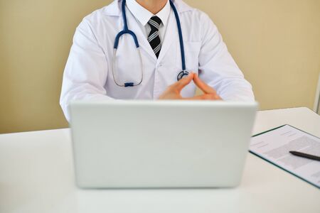 Smiling doctor posing in the office, he is wearing a stethoscope, medical staff on the hospital...