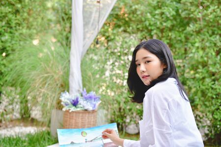 Concept Artist Beautiful girl. Beautiful women are creating art. Beautiful woman is painting happily. Young artist painting outside the house.の写真素材