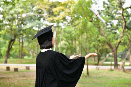 Graduation Concept. Graduated students on graduation day. Asian students are smiling happily on the graduation day. Students wear graduation gowns in the gardenの写真素材