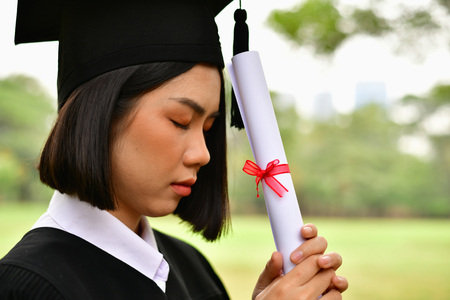 Graduation Concept. Graduated students on graduation day. Asian students are smiling happily on the graduation day. Students wear graduation gowns in the gardenの写真素材