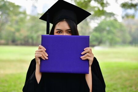 Graduation Concept. Graduated students on graduation day. Asian students are smiling happily on the graduation day. Students wear graduation gowns in the gardenの写真素材