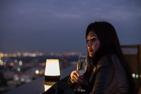 Concept of business celebrations. Asian businesswoman is drinking alcohol in the party. Young businesswoman celebrates the success of her work. Young businesswoman drinking in a business bar.の写真素材
