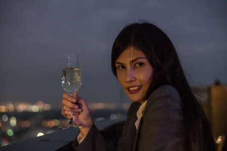 Concept of business celebrations. Asian businesswoman is drinking alcohol in the party. Young businesswoman celebrates the success of her work. Young businesswoman drinking in a business bar.の写真素材