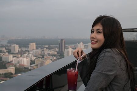 Concept of business celebrations. Asian businesswoman is drinking alcohol in the party. Young businesswoman celebrates the success of her work. Young businesswoman drinking in a business bar.の写真素材