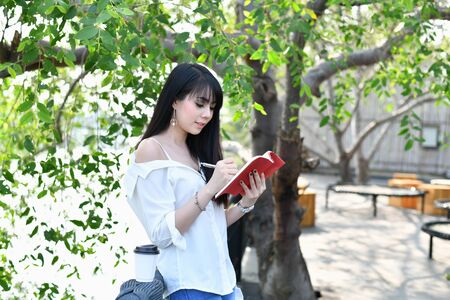 Education Concepts. Asian women reading books in the park. Beautiful women are relaxing in the park. Beautiful women are happy to read.の写真素材