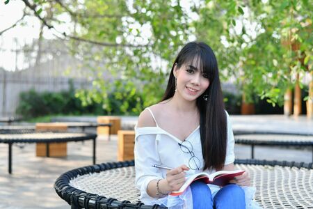 Education Concepts. Asian women reading books in the park. Beautiful women are relaxing in the park. Beautiful women are happy to read.の写真素材