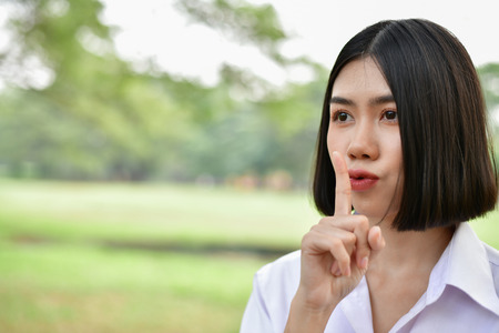 Education Concepts. Beautiful student do not say (silent). Beautiful young students are keeping secret. Beautiful young student is speaking with a soft voice.の写真素材
