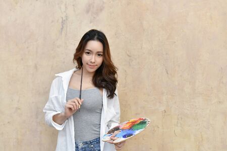Concept Artist Beautiful girl. Beautiful women are creating art. Beautiful woman is painting happily. Young artist painting in the gallery.の写真素材