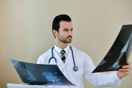 Smiling doctor posing in the office, he is wearing a stethoscope, medical staff on the hospital...