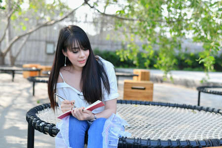 Education Concepts. Asian women reading books in the park. Beautiful women are relaxing in the park. Beautiful women are happy to read.の写真素材