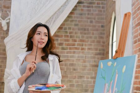 Concept Artist Beautiful girl. Beautiful women are creating art. Beautiful woman is painting happily. Young artist painting in the gallery.の写真素材
