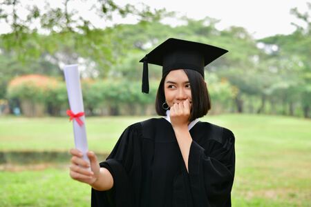 Graduation Concept. Graduated students on graduation day. Asian students are smiling happily on the graduation day. Students wear graduation gowns in the gardenの写真素材
