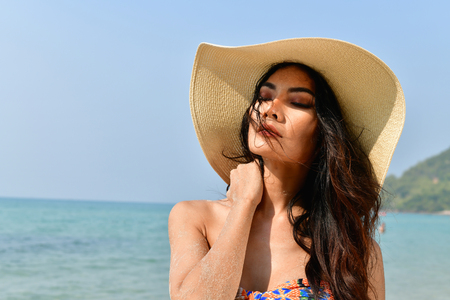 Sexy girl concept in swimsuit. Beautiful woman wearing a swimsuit playing in the beach. Girl in sexy swimsuit poses seductively. Sexy girl seduces a young man on the beach.の写真素材