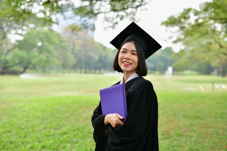 Graduation Concept. Graduated students on graduation day. Asian students are smiling happily on the graduation day. Students wear graduation gowns in the gardenの写真素材