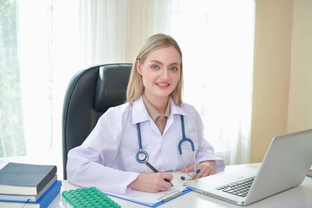 Doctor Concept. Smiling doctor posing in the office. Young doctor is wearing a stethoscope. medical staff on the hospital background. The doctors are happy to work.の写真素材