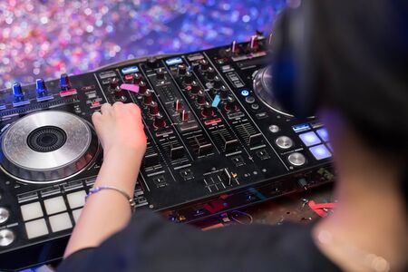 Music Concepts. DJ is rhythm music with Controller and mixer. DJ is playing the song at the party. Young are adjusting the music with the controller. The fun of music and light colors.の写真素材