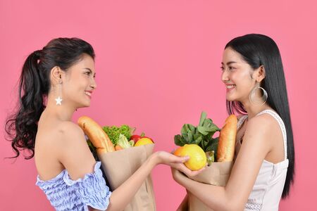 shopping concepts. Beautiful girls are buying fruits and vegetables. Beautiful girl to buy healthy food. Beautiful girl shopping at the bazaar. Asian girl suffocating bags of fruits and vegetablesの写真素材