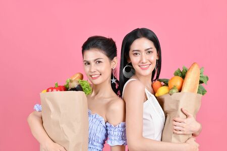 shopping concepts. Beautiful girls are buying fruits and vegetables. Beautiful girl to buy healthy food. Beautiful girl shopping at the bazaar. Asian girl suffocating bags of fruits and vegetablesの写真素材