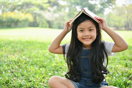 Education Concepts. The girl is reading a book in the garden. Beautiful girl is seriously studying. Beautiful girls are happy learning.の写真素材