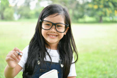 Education Concepts. The girl is reading a book in the garden. Beautiful girl is seriously studying. Beautiful girls are happy learning.の写真素材