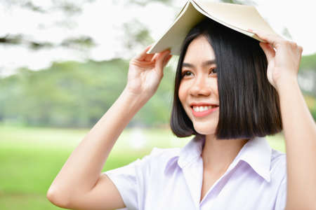 Education Concepts. Beautiful student reading books in the park. Beautiful girl are relaxing in the park. Young student are happy to read. Young student love to study. Education of Asian Women.の写真素材