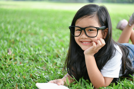 Education Concepts. The girl is reading a book in the garden. Beautiful girl is seriously studying. Beautiful girls are happy learning.の写真素材