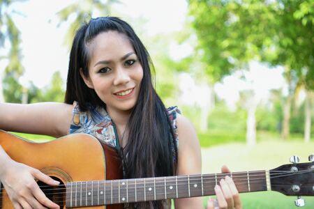 Music Concepts. Asian girls playing guitar. Asian women relaxing with music. Asian women have a...