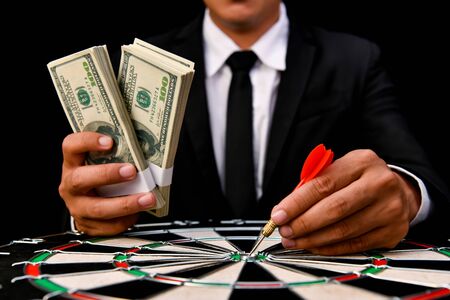 Finance Business Concepts. Businessman is playing darts. Businessmen are aiming for work. Businessman looking at a lot of money.の写真素材