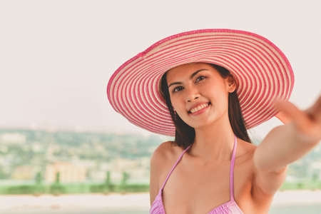 Swimsuit Concept. Beautiful girl wearing pink swimsuit. Beautiful girl in swimwear is relaxing at the swimming pool. Independent living sexy woman at the city center pool.の写真素材