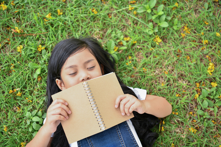 Education Concepts. The girl is reading a book in the garden. Beautiful girl is seriously studying. Beautiful girls are happy learning.の写真素材