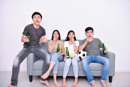 Concept of cheering. Asian teenagers watching football on television. People are cheering and winning football scores.の写真素材