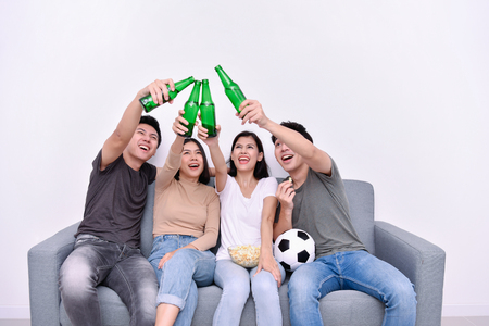 Concept of cheering. Asian teenagers watching football on television. People are cheering and winning football scores.の写真素材