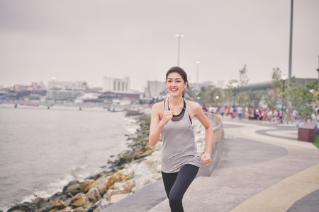 Sports concept. Beautiful girl is exercising on the beach with running. Beautiful girl is happy to exercise. 
Beautiful girls like to exercise by running. People are exercising on the beach.の写真素材