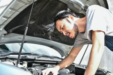 Car Repair Concept. Asian people are repairing cars on the roadside. Asian guy fixes car with confidenceの写真素材
