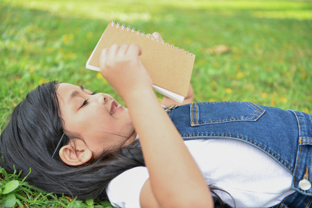 Education Concepts. The girl is reading a book in the garden. Beautiful girl is seriously studying. Beautiful girls are happy learning.の写真素材