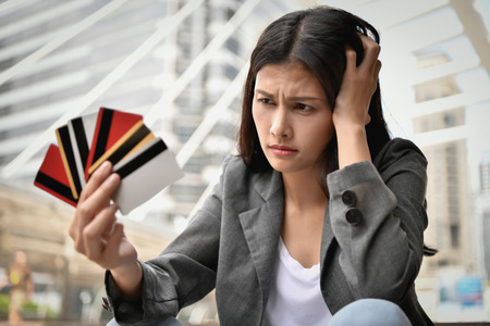 Concept of unemployed. Young business woman is stressed because of no money. Young businesswoman looking at the bill of credit.の写真素材