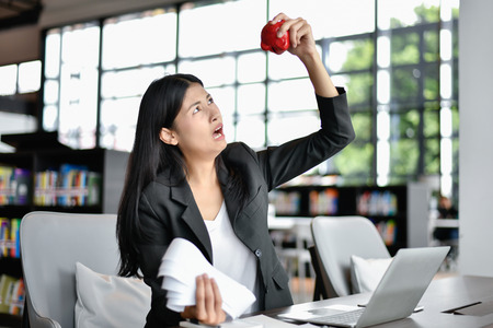 Business concept. Young business woman is stressed about her expenses. Young businessmen are smashing a piggy bank.の写真素材