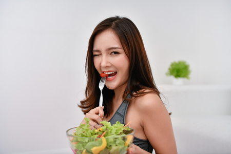 The concept of nutritional food. Beautiful girl takes care of her health by eating vegetables. Young athletes choose a good diet.の写真素材