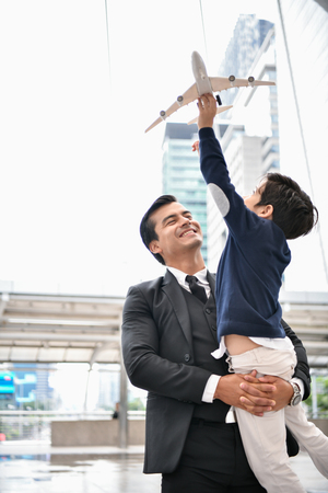 Family concept. Dad and son are playing fun toys. A businessman is carrying his son inside the city.の写真素材