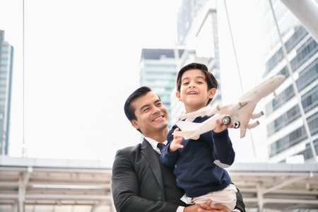 Family concept. Dad and son are playing fun toys. A businessman is carrying his son inside the city.の写真素材