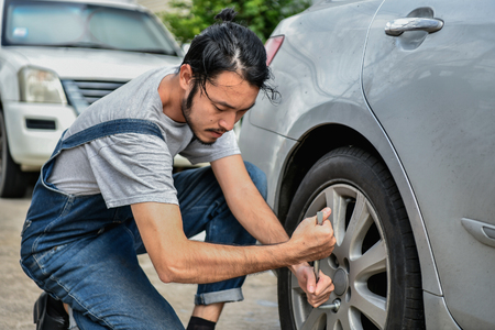 Car Repair Concept. Asian people are repairing cars on the roadside. Asian guy fixes car with confidenceの写真素材