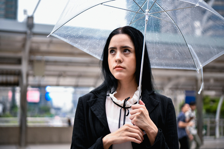 Holiday concept. Young businesswoman walking in the rain. Beautiful young woman looking at the rain.の写真素材