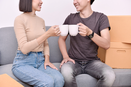 Moving house Concept. Asian young man is carrying his belongings. Young Asian women are holding their stuff in a paper box. Young are happy in the new house.の写真素材