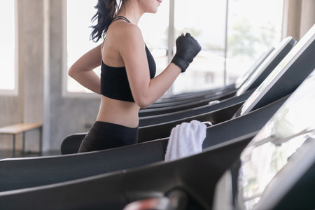 Exercise concept. Attractive young sports woman is working out in gym. Doing cardio training on treadmill.の写真素材