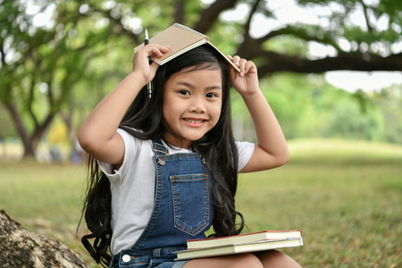 Education Concepts. The girl is reading a book in the garden. Beautiful girl is seriously studying. Beautiful girls are happy learning.の写真素材