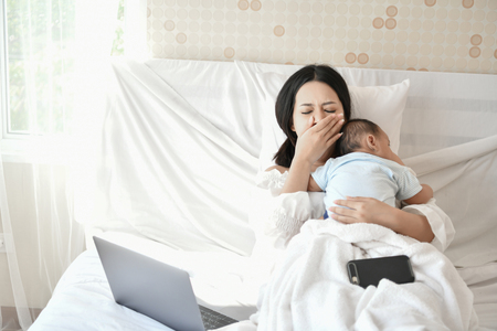Newborn Concept. Mom took work to do at home to have time to take care of the baby.の写真素材