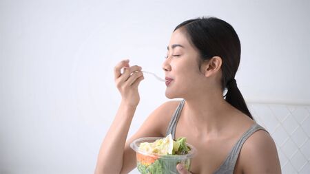 Health concept. Women are eating delicious fruits and vegetables within the bedroom.の写真素材