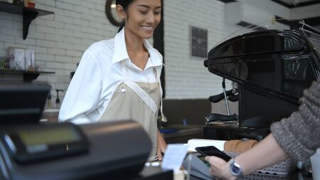 Coffee shop concept. The girl is suggesting that customers pay through the payment machine. 4k...